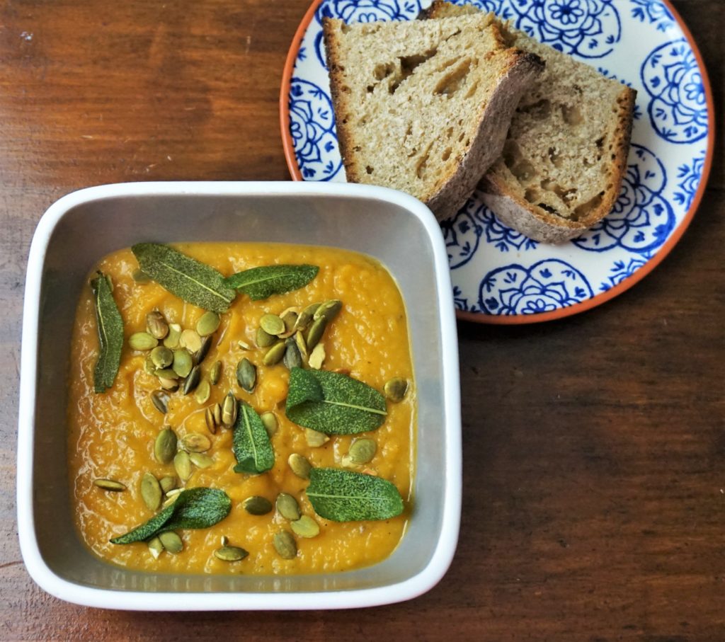 Roasted butternut squash and garlic soup with toasted pumpkin seeds and crispy sage leaves served with beer bread