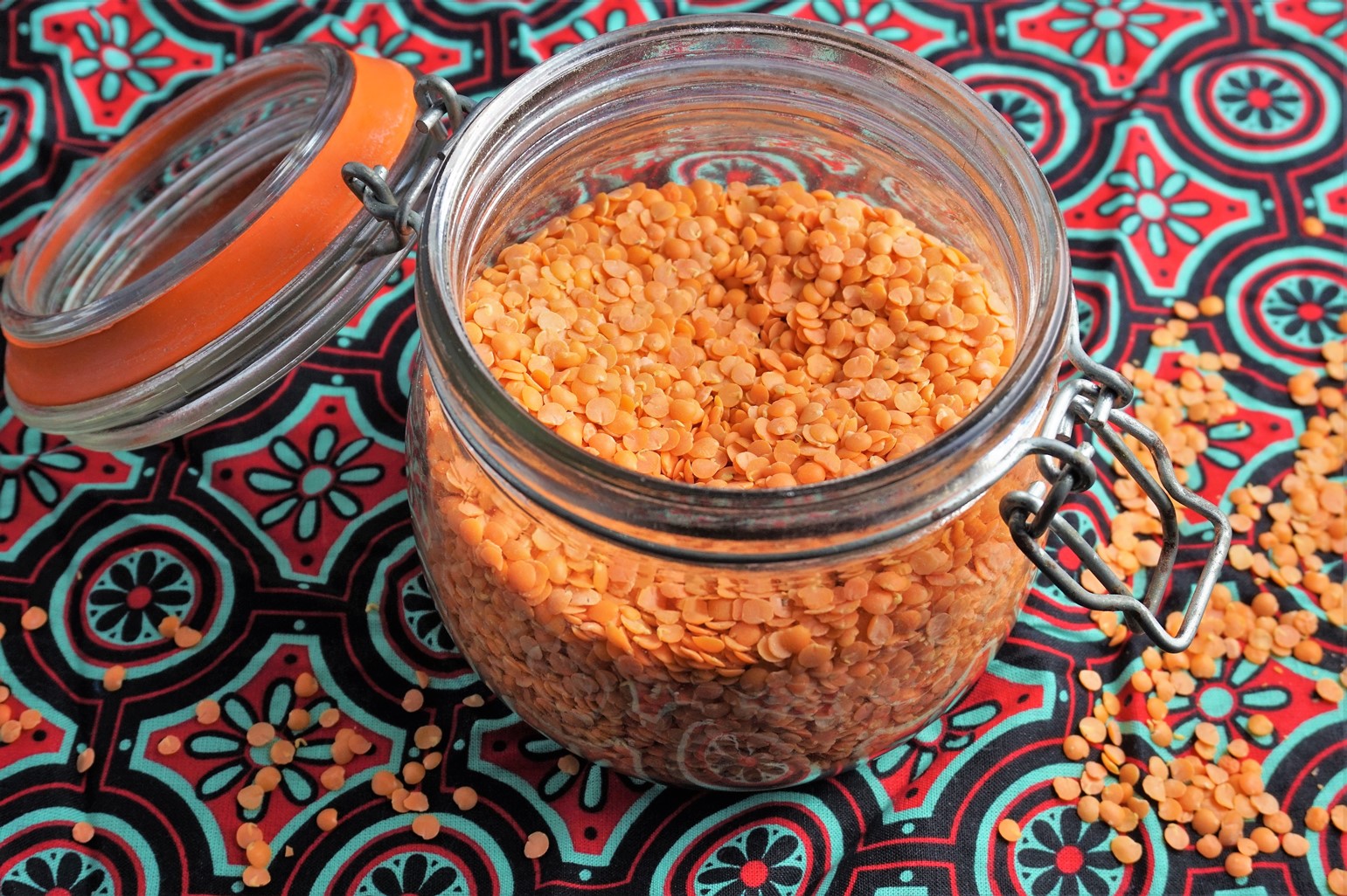 a jar of red lentils on a brightly coloured patterned cloth