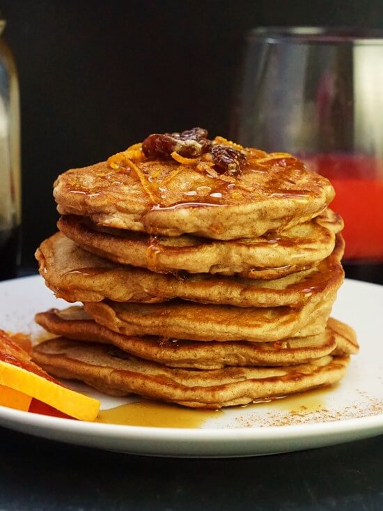 A stack of Sultana, Orange & Cinnamon Pancakes topped with maple syrup