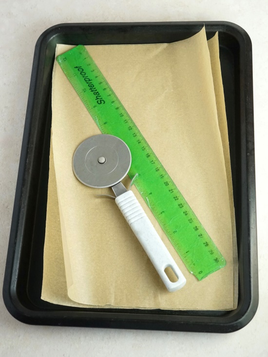 baking tray, paper, cutting tool and ruler for making homemade crackers